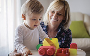 photo représentant une assistante maternelle jouant avec un petit enfant