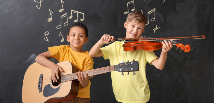 Des enfants face à un tableau à craie jouant d'un instrument chacun (guitare et violon)
