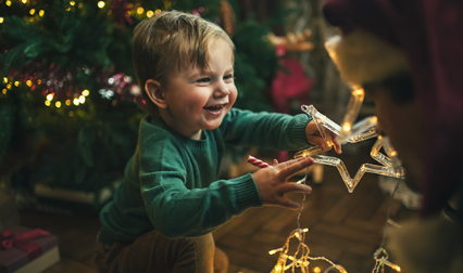 Un jeune enfant devant un sapin décoré aux couleurs de Noël