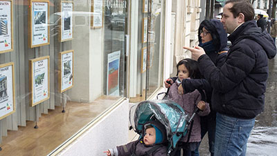 couple devant la vitrine d'une agence immobilière