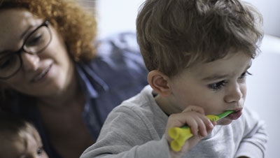 Maman qui surveille son enfant pendant qu'il se brosse les dents