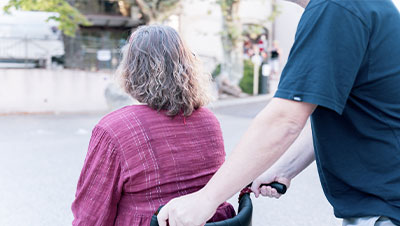 Un homme poussant le fauteuil d'une femme en situation de handicap