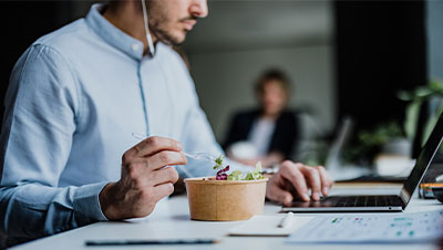 un salarié déjeune devant son ordinateur