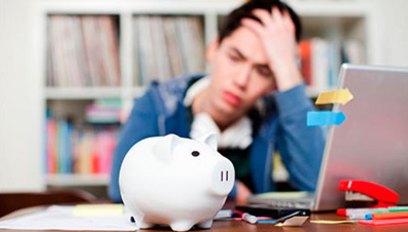 étudiant qui se tient la tète devant sa tirelire